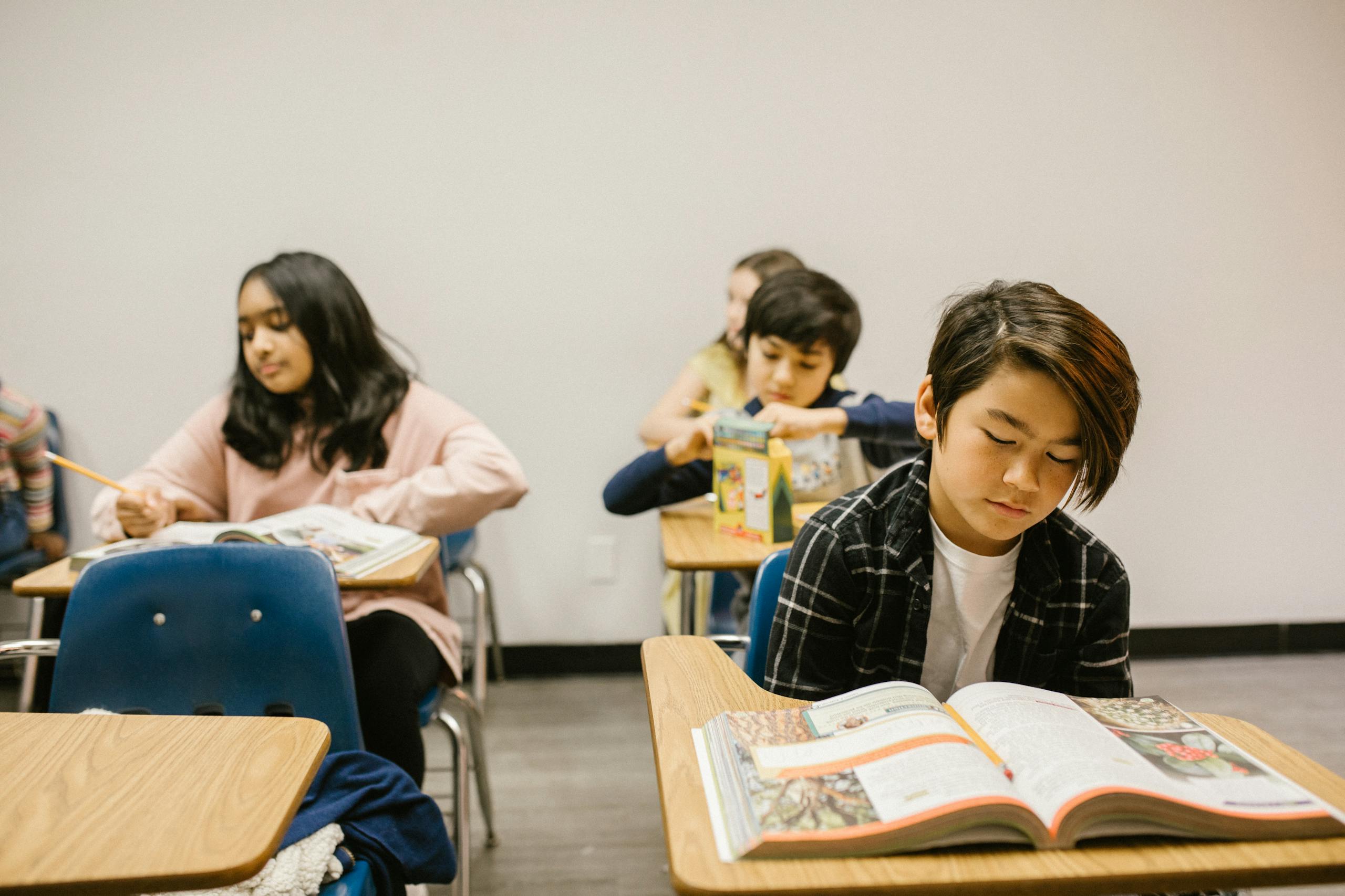 A diverse group of students reading and studying in a classroom setting, focusing on education.